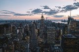 Fototapeta Nowy Jork - Aerial view of skyscrapers and towers in midtown skyline of Manhattan with evening sunset sky. Scenery cityscape of financial district with famous New York Landmark, illuminated Empire State Building