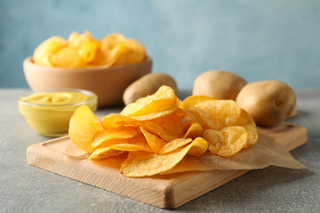 Wall Mural - Potato chips. Beer snacks, sauce, potato on cutting board, on grey background, space for text. Closeup