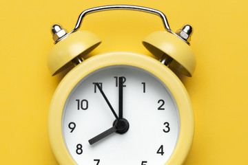 Wall Mural - Yellow round alarm clock on the yellow background.