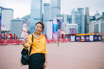 Wall Mural - Young Asian woman taking selfie on urban background