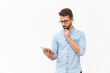© Mangostar - Sad frowning guy with tablet reading content on screen. Handsome young man in casual shirt and glasses standing isolated over white background. Wireless internet concept