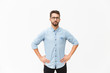 © Mangostar - Front of serious determined guy keeping hands on hip. Handsome young man in casual shirt and glasses standing isolated over white background. Male portrait concept