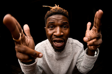 Fish-eye photo black man with blonde dreadlocks posing looking at camera makes pistols from fingers