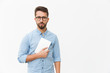 © Mangostar - Serious guy in eyeglasses holding tablet and looking at camera. Handsome young man in casual shirt and glasses standing isolated over white background. Tablet user concept