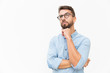 Pensive customer thinking over special offer, touching chin, looking up. Handsome young man in casual shirt and glasses standing isolated over white background. Advertising concept