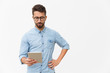 © Mangostar - Focused tablet user reading content on screen. Handsome young man in casual shirt and glasses standing isolated over white background. Wireless internet technology concept