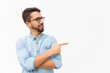Positive male customer presenting new product, pointing finger at copy space. Handsome young man in casual shirt and glasses standing isolated over white background. Presentation concept