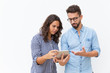 © Mangostar - Serious puzzled couple reading message on tablet screen. Young woman in casual and man in glasses in glasses posing isolated over white background. Networking concept