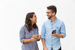 © Mangostar - Happy excited couple with smartphones discussing awesome news. Young woman in casual and man in glasses in glasses posing isolated over white background. Mobile app or good news concept