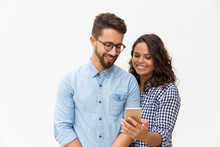 Happy Cheerful Woman Showing Message On Phone To Her Boyfriend. Young Woman In Casual And Man In Glasses In Glasses Posing Isolated Over White Background. Good News Concept