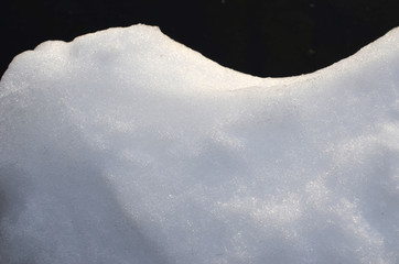 white sparkling snow close up against dark background - winter snow wallpaper, sunlight