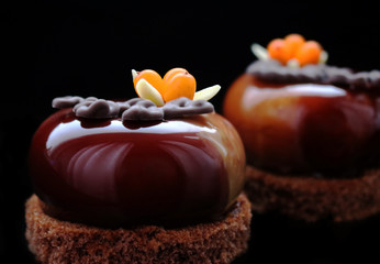 Dark brown glazed desserts with buckthorn berries and almonds on brownie base