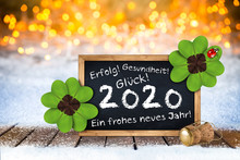 Bottle Of Champagne Glasses Cork Blackboard German Greeting Frohes Neues Jahr 2020 Greetings (english Translation: Happy New Year 2020 ) Card Wooden Planks Front Bright Golden Bokeh Light Background