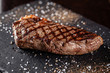 Farm organic food concept. Grilled beef steak with grill. Fried steak on on black slate, on a black background.