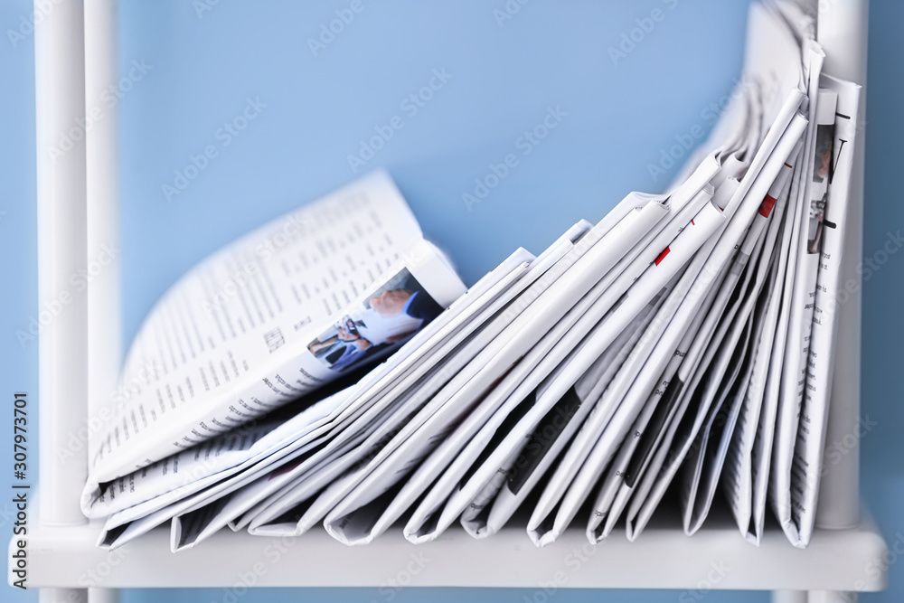 Many newspapers on shelf near color wall