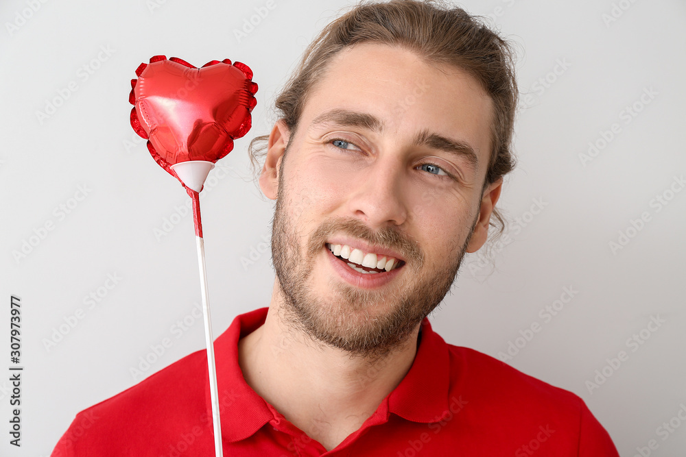 Handsome man with heart on light background. Valentine's Day celebration
