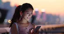 Woman Use Of Mobile Phone At Beautiful Sunset Time