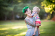 A portrait of Caucasian young woman with green hair and tattoo holding a blond toddler boy in her hands. Hugging, Mother's day concept
