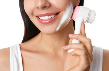 Canvas Print - Young woman using facial cleansing brush on white background, closeup. Washing accessory