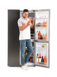 © New Africa - Man with bottle of juice near open refrigerator on white background