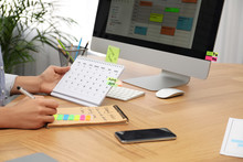 Woman Making Schedule Using Calendar At Table In Office, Closeup