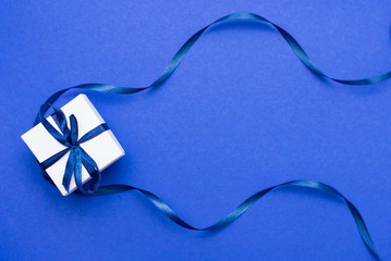 gift box wrapped with classic blue ribbon on blue background. top view. copy space