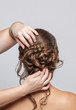 © Dimid - Portrait of a beautiful sensual light brown haired woman with a wedding hairstyle in a beauty salon. The hairdresser does the hairstyle. Wedding hairstyle.