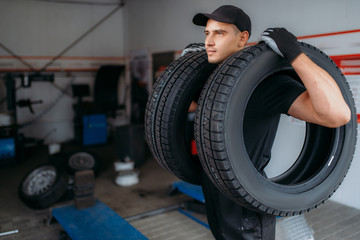 Wall Mural - Auto repairman holds two tires, repairing service