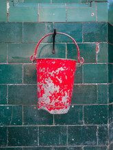 Old Red Bucket On Green Tiled Wall.