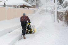 Man Operating Snow Blower To Remove Snow On Driveway. Man Using A Snowblower. A Man Cleans Snow From Sidewalks With Snowblower