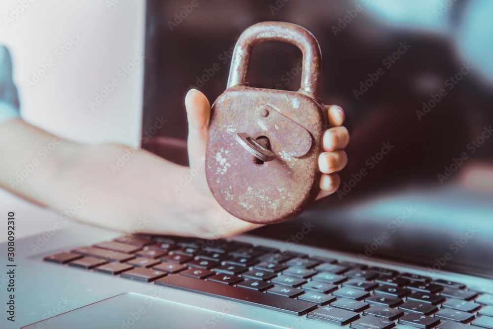 Young business girl holding old rusty lock against laptop computer as ...