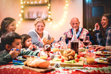 Multi Generation Big Family Having Fun At Christmas Supper Party - Winter Holiday X Mas Concept With Grand Parent And Children Eating Together At Home Dinner - Focus On Dog Puppy Toy With Reindeer Hat