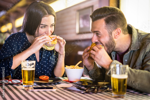 Fotografía Happy couple having fun eating burger at restaurant pub fast food - Young people