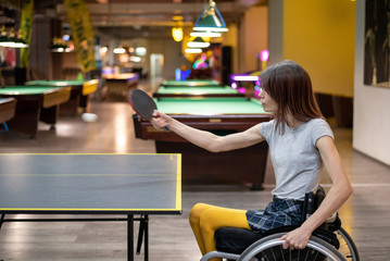 Young disabled woman in a wheelchair playing table tennis