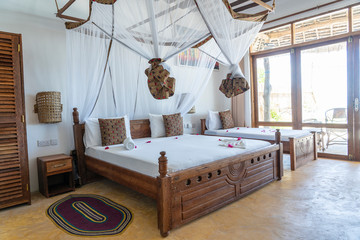 Interior design decor furnishing of luxury show home holiday villa bedroom with four poster bed. Interior design of the tropical villa on the sea on the island of Zanzibar, Tanzania, Africa