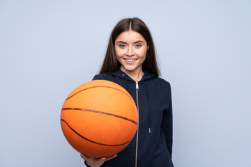 Wall Mural - Young woman over isolated blue background with ball of basketball