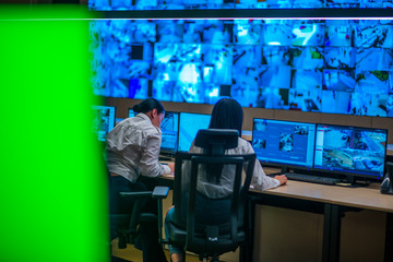 Female security guards working in surveillance room, monitoring cctv and discussing.