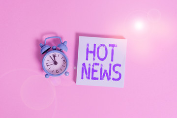 Writing note showing Hot News. Business concept for subject that experiences surge in popularity on social media Vintage alarm clock wakeup blank notepad sticky note colored background