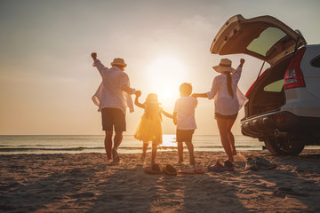 Wall Mural - Family vacation holiday, Happy family running on the beach in the evening. Back view of a happy family on a tropical beach and a car on the side.