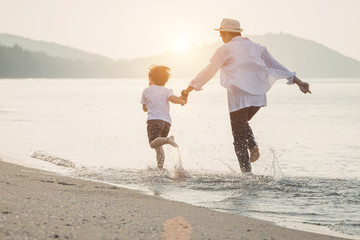 Wall Mural - Happy family with little boy walking together on a tropical beach during the summer holidays.