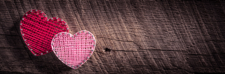 Wall Mural - two heart shapes made of yarn and nails on rustic wooden background with dark vignette - valentine's