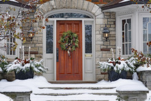 Front Door Of Snow Covered House With Christmas Wreath