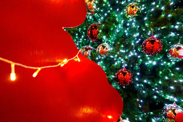 Wooden red backdrop and little christmas light illuminated with metallic red and golden balls ornament decorated on green pine tree for Merry Christmas and Happy New Year seasonal event party