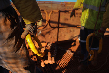 Wall Mural - Defocused of construction male rigger hands wearing a heavy duty safety protection glove while holding lifting dragging crane hook on open field construction site   