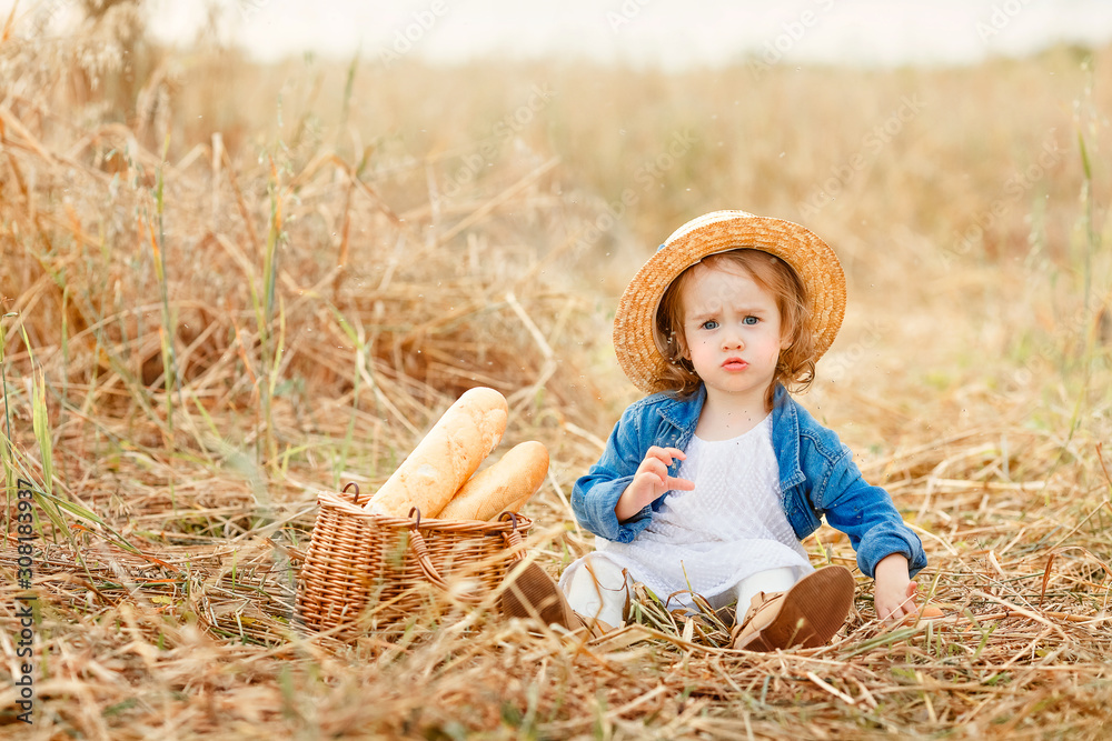 Portrait of a sweet beautiful little girl in straw hat sitting in a ...