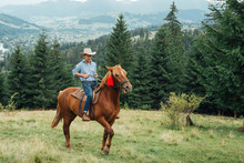 Cowboy Riding A Horse Over The Mountains. Portrait Of A Cowboy Riding A Horse