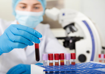 Poster - Blurred lab assistant in protective medical clothes choosing blood sample