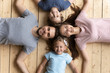 © fizkes - Above view couple and kids lying on wooden warm floor