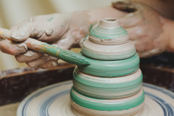 Wall Mural - Hands on pottery wheel. Craftsman artist painting pot with brush