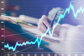 Financial forex graph displayed on hands taking notes background. Concept of research. Multi exposure